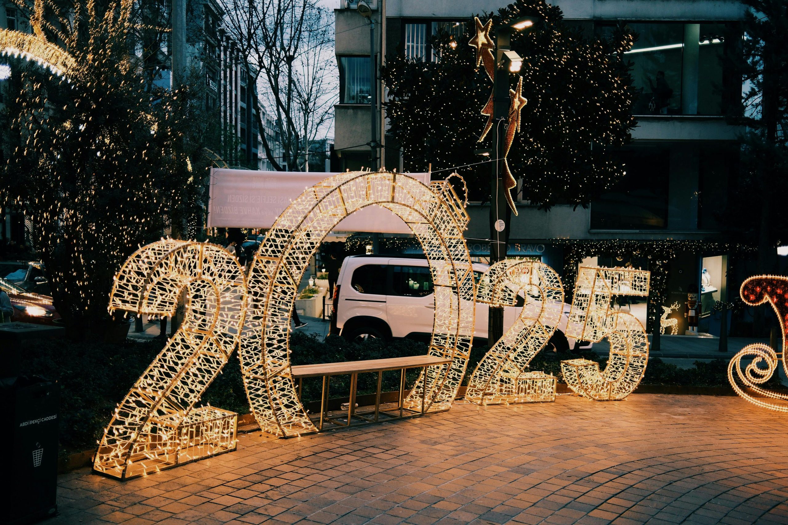Illuminated 2025 sign on city street with decorative lights creating a festive atmosphere.